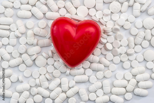 Scattered white tablets with red heart on it, isolated