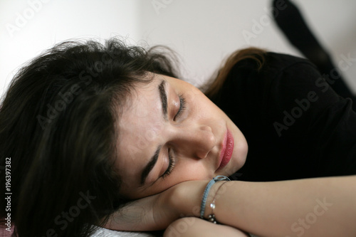 Woman is sleeping; closeup portrait of a tired young woman sleeping in a bed.