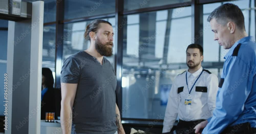 Man in guard uniform conducting checking control with metal detector working with passenger in airport. 4K shot on Red cinema camera. Man in guard uniform conducting checking control with metal detector working with passenger in airport. 4K shot on Red cinema camera.
