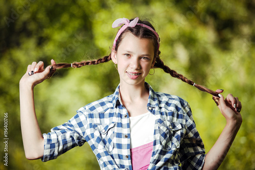 Happy teenage girl holding herself for pigtails.