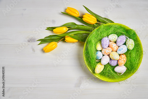 beautiful easter decoration with eggs and yellow tulips on a white wooden table