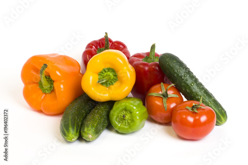 Red yellow and orange peppers with tomatoes on a white background. Cucumbers with colorful peppers in composition on a white background. © liubovi samoilova