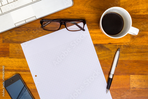 Working desk with Laptop, Blank Paper, Pen, Mobile Phone, Glasses, Coffee