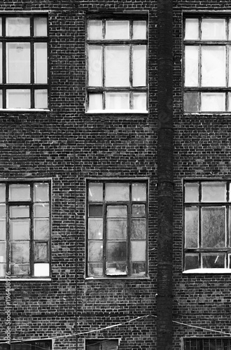 Facade of an old brick building in loft style. High Windows and textural materials. Black and white styling
