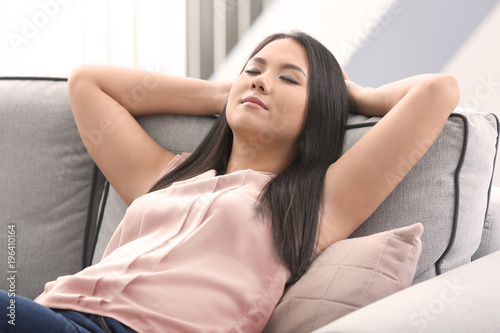 Young woman relaxing on cozy sofa in light room