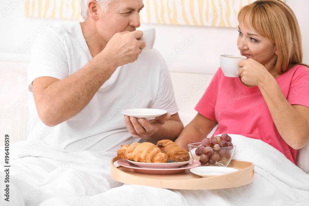Mature couple having breakfast in bed. Romantic morning