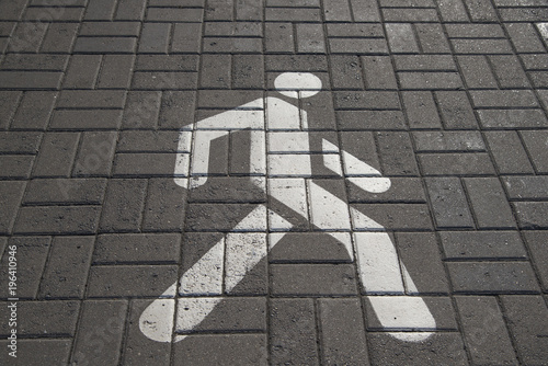 Drowed walking figure on the paving slab. Pedestrian sign on pavement. Road and signs. photo