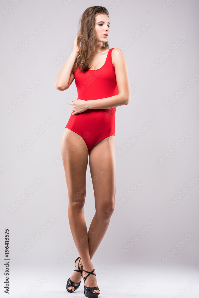Full body of perfect slim woman wearing red swimsuit isolated on gray background