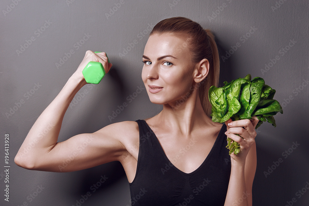 girl in sports top holds gattelu and bunches of spinach