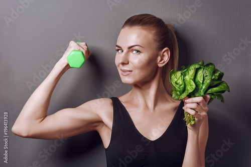 Obraz na płótnie girl in sports top holds gattelu and bunches of spinach w salonie