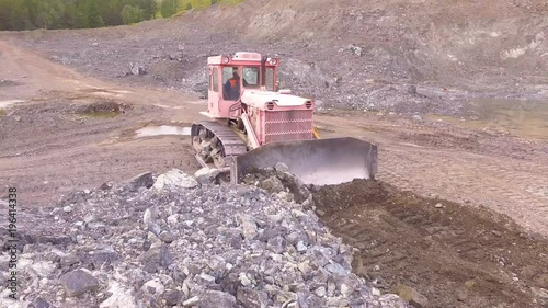 Old caterpillar bulldozer move the huge stones. Heavy production, extraction of gravel, summer landscape. Quarry for gravel extraction.