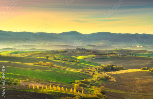 Tuscany countryside misty panorama, rolling hills and green fields on sunset. Pisa, Italy