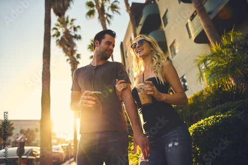 trendy attractive couple walking together with coffee in los angeles