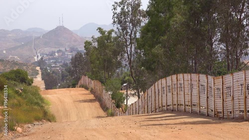 The U.S. border wall fence with the city of Tecate Mexico background. photo