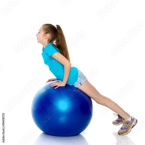 little girl doing exercises on a big ball for fitness.