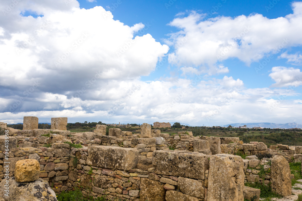 SICILY, TRAPANI, SELINUNTE: Ancient greek temple at the archeological site of Selinunte, Trapani, during a sunny day with clouds, green fields and a perfect blue sky of early spring.