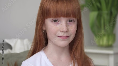 Little happy ginger girl with freckles in a white room