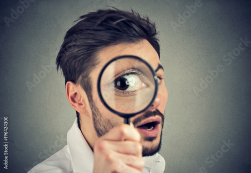 Curious man looking through a magnifying glass