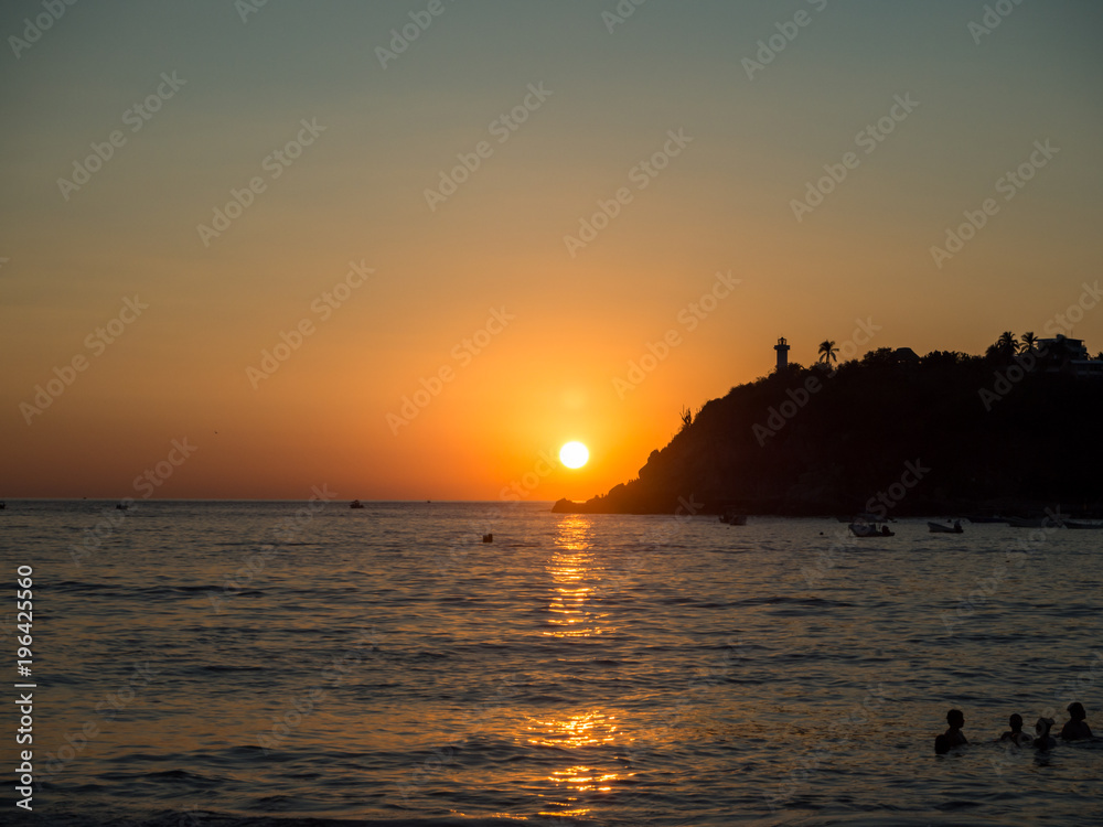 Puerto Escondido, Oaxaca, Mexico, South America - January 2018: [Sunset at the local beach, lighthouse, crowdwed beach, tourist destination]