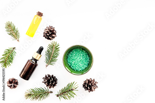Pine spa cosmetics, products for skin care. Fir essential oil and green aromatic spa salt near branches and cones on white background top view copy space