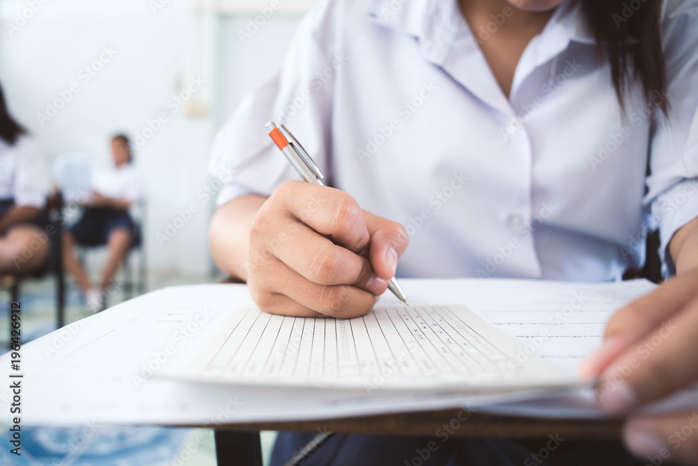 Students writing pen in hand doing exams answer sheets exercises in classroom with stress. Students writing pen in hand doing exams answer sheets exercises in classroom with stress.