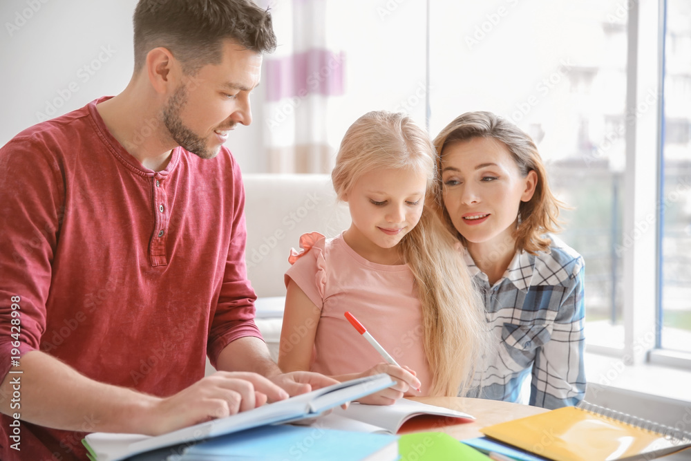 Little girl with parents doing homework at home