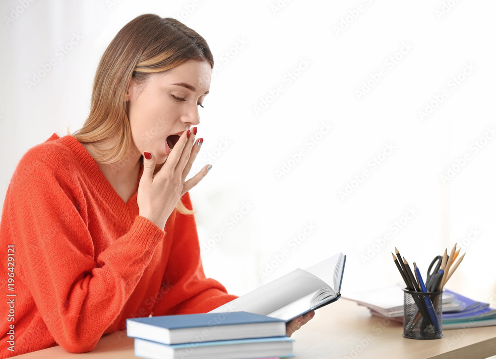 Tired pretty student studying at table indoors Tired pretty student studying at table indoors
