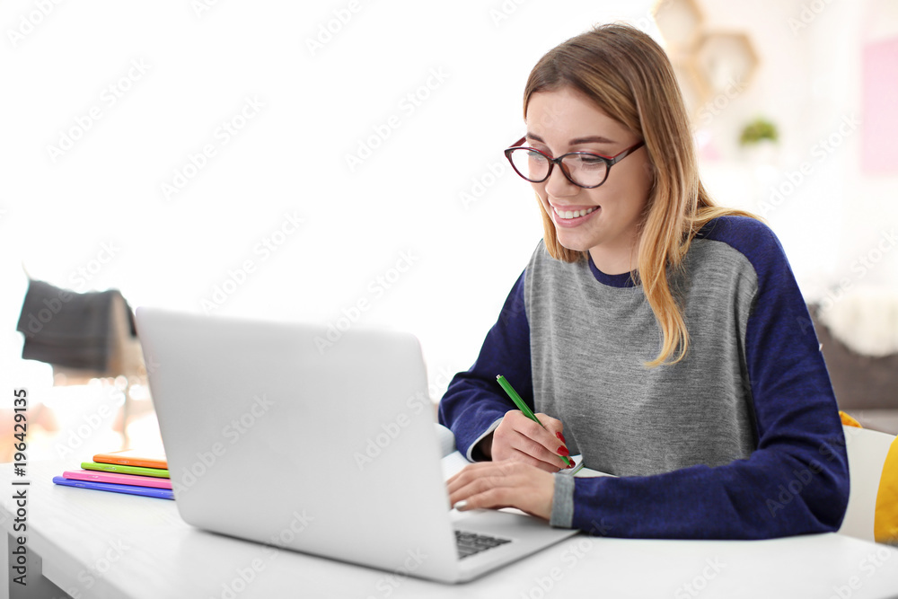 Pretty student with laptop studying at table indoors Pretty student with laptop studying at table indoors