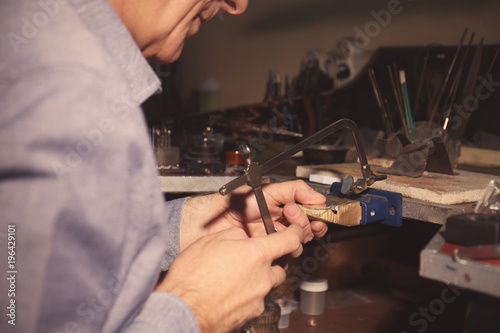 Jeweler using piercing saw in workshop