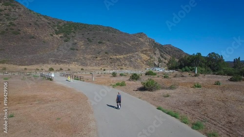 Aerial footage following a man riding an electric unicycle down a road in California. photo