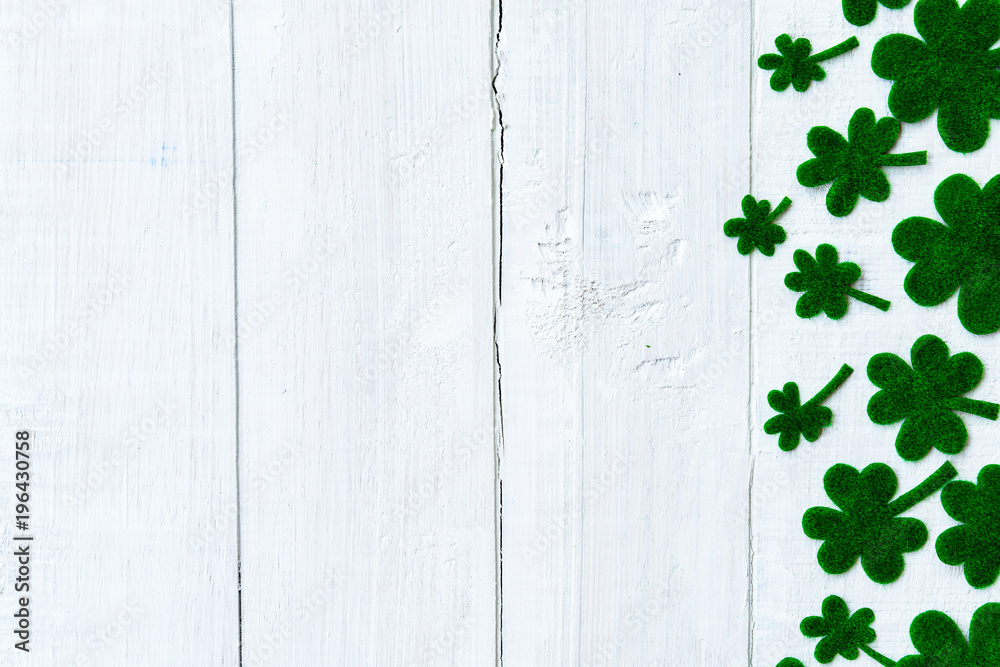 Happy St Patricks Day message and a lot of green paper clover leaf on white wooden background Happy St Patricks Day message and a lot of green paper clover leaf on white wooden background