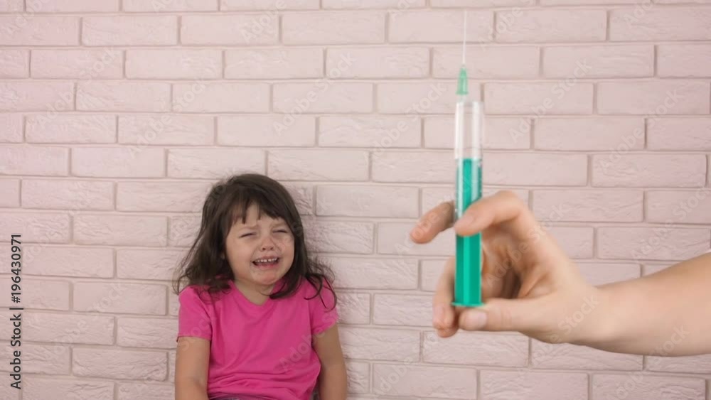 Fear of injection. A little girl is afraid of a doctor with a syringe. Sick child. Fear of injection. A little girl is afraid of a doctor with a syringe. Sick child.
