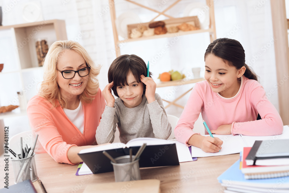 Grandmother helps to make lessons for grandchildren. Beautiful granny helps children learn. Grandmother helps to make lessons for grandchildren. Beautiful granny helps children learn.