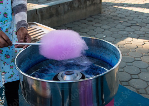 Pink cotton candy is spuning in machine. Cotton candy, candy floss or fairy floss is a form of spun sugar with air.