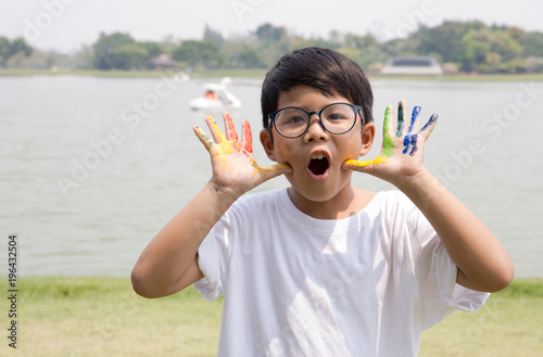 Asian boy in white t-shirt with colorful paint on his finger with garden scene