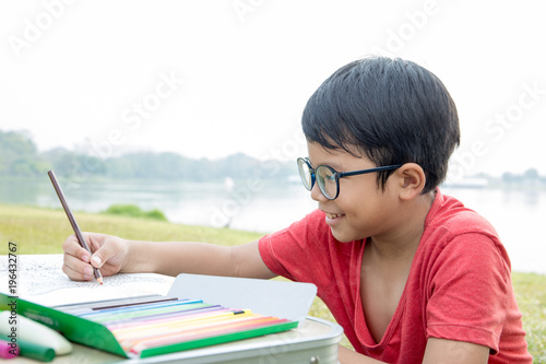 Asian boy wear red t-shirt color a picture in a garden with pond scene