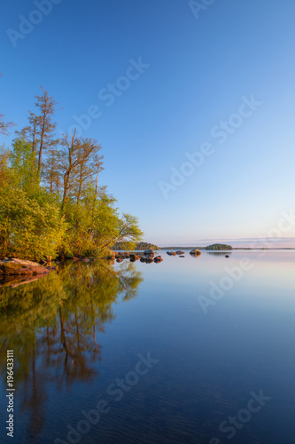 Calm lakeside at sunset and rocks on the water