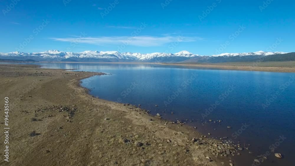 A beautiful aerial over a mountain lake reveals the Sierra Nevada mountains in winter. A beautiful aerial over a mountain lake reveals the Sierra Nevada mountains in winter.