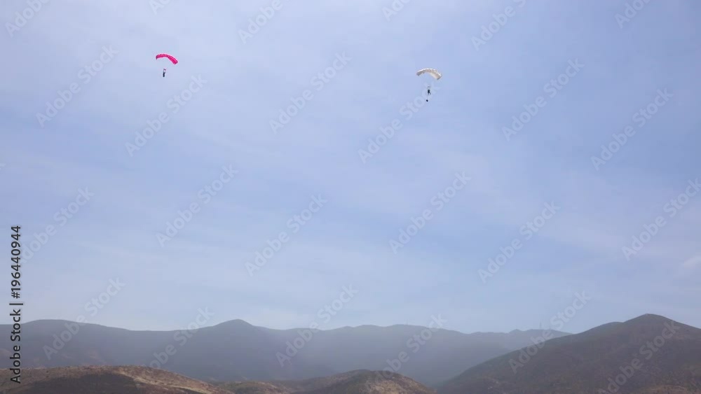 Elite military forces and paratroopers skydive onto and land in a field during training operations. Elite military forces and paratroopers skydive onto and land in a field during training operations.
