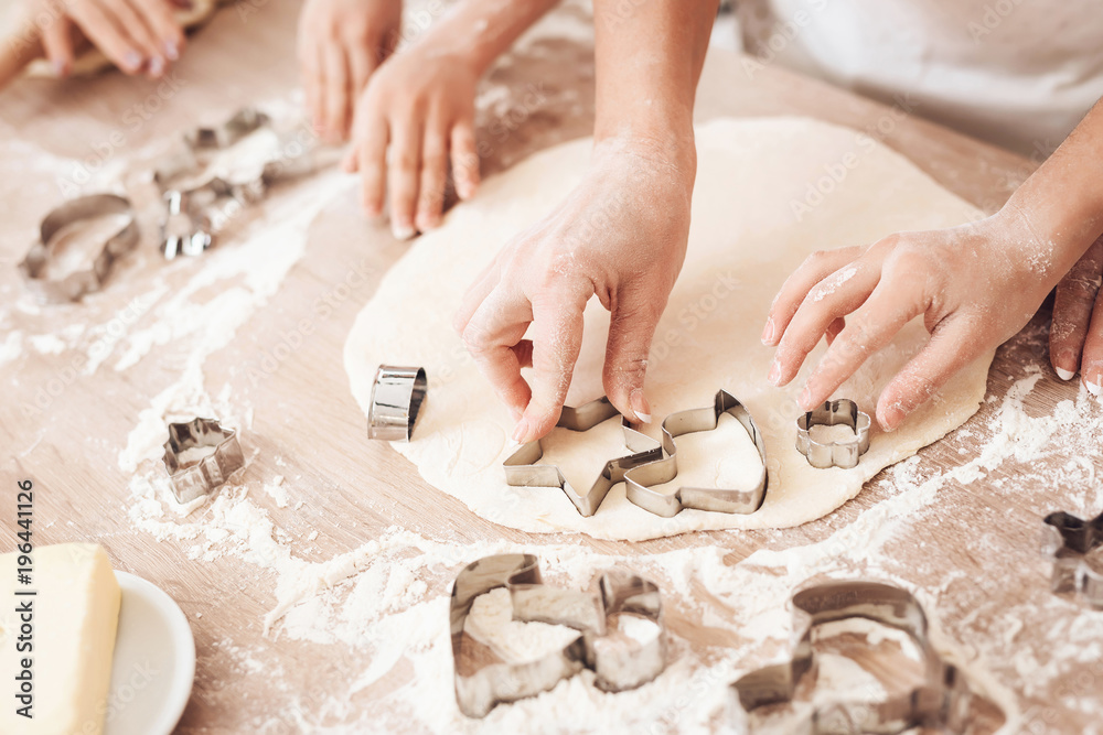 Female and children's hands make form for biscuits with help of baking molds.