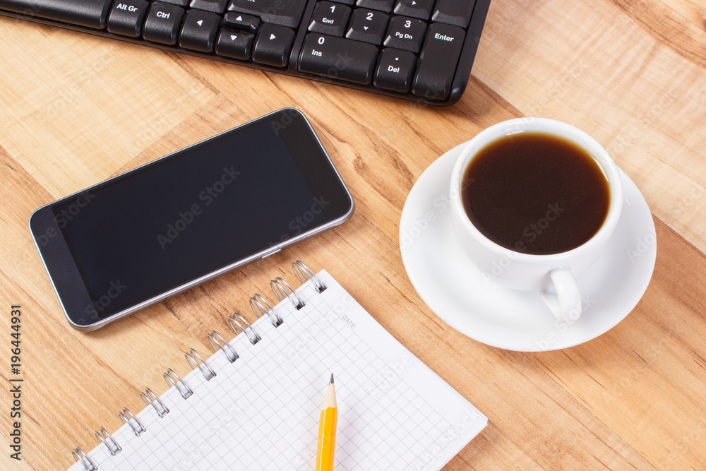 Mobile phone with notepad for writing notes and cup of coffee, using electronics concept Mobile phone with notepad for writing notes and cup of coffee, using electronics concept