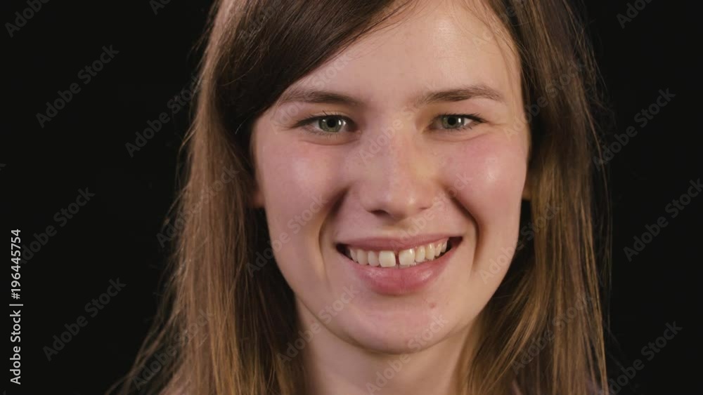 A beautiful young lady's face smiling against a black background. Close-up shot A beautiful young lady's face smiling against a black background. Close-up shot