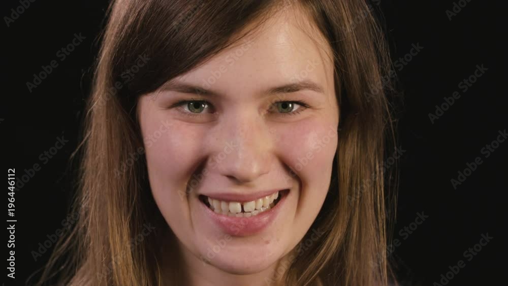 A beautiful young lady's face smiling against a black background. Close-up shot A beautiful young lady's face smiling against a black background. Close-up shot