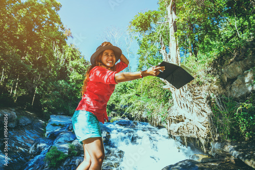 Fototapeta Naklejka Na Ścianę i Meble -  Asian woman travel nature. Travel relax. Study read a book. Nature Education Write a note At Waterfall Use summer. In Thailand