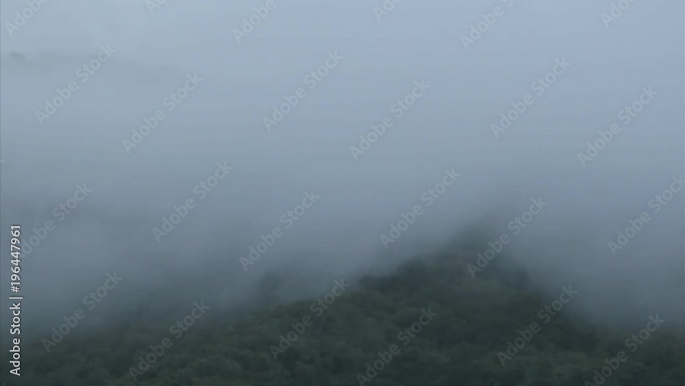 A thick blanket of fog rolls over a mountain hillside. A thick blanket of fog rolls over a mountain hillside.