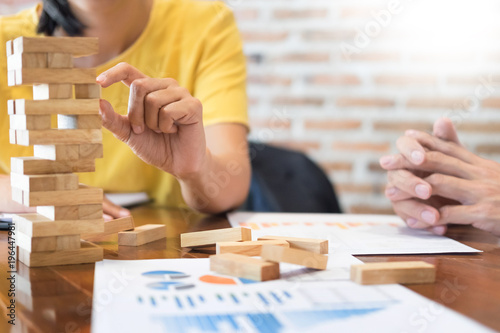 Group of business creative people building tower by wooden blocks, doing a plan for brainstrom business strategy, risk, future, teamwork concept.