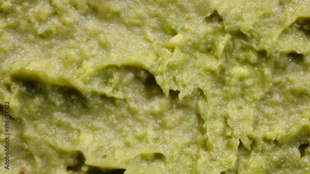 Extreme closeup top view of avocado smash rotating in 4K. Traditional tasty sauce guacamole.
