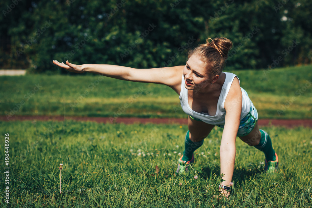 Female athlete does sport exercises in the stadium