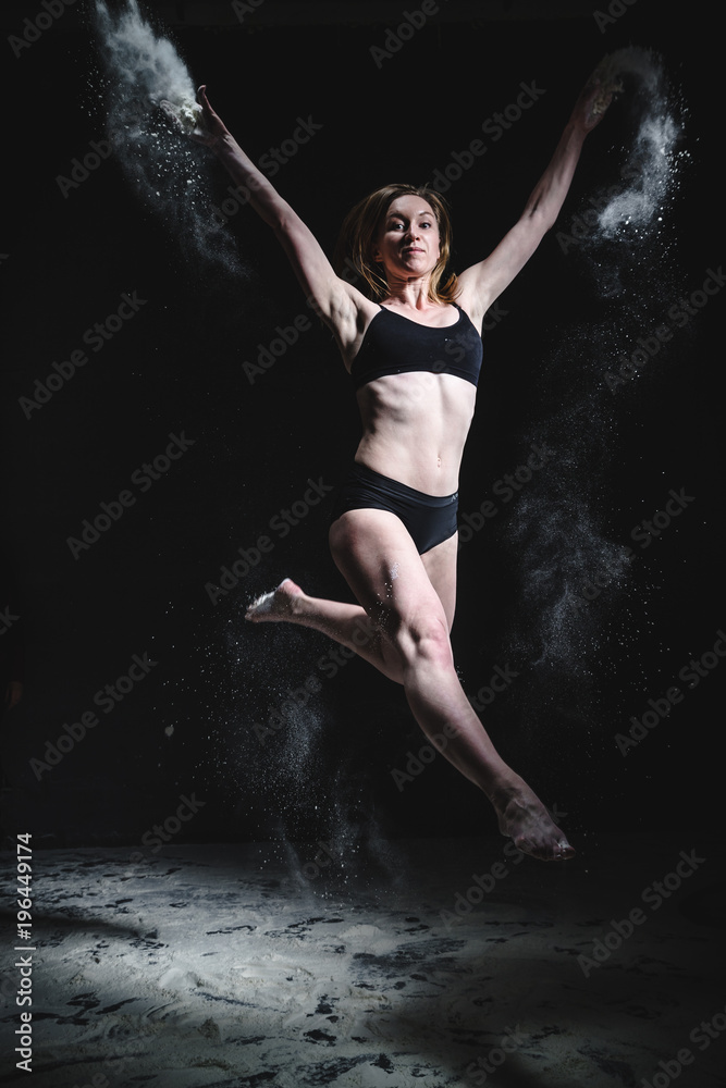 Obraz premium Girl dansing with flour on black background