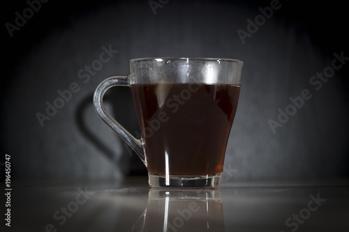 A glass with hot soaring tea on a black background.
